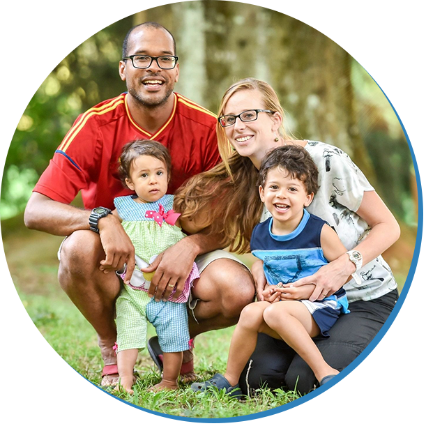 A family posing for the camera in front of some trees.